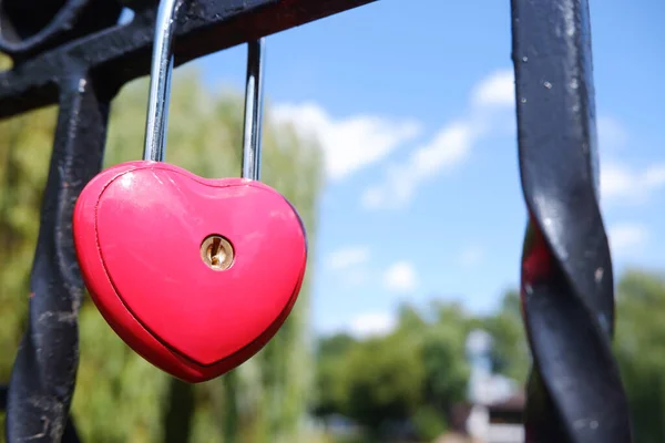 Cerradura de puerta roja de metal en forma de corazón en la valla como símbolo del amor eterno. — Foto de Stock