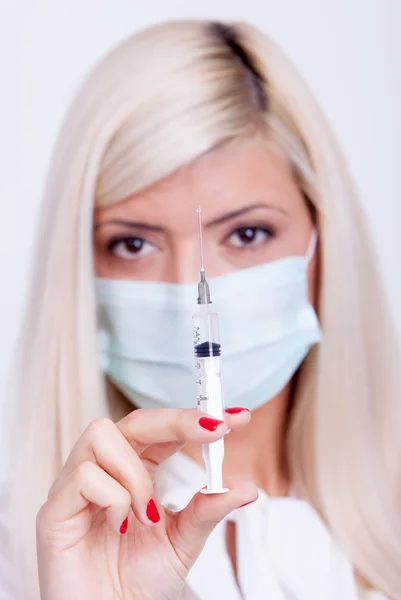 Женщина-врач или медсестра в медицинской маске держит шприц с инъекцией — стоковое фото