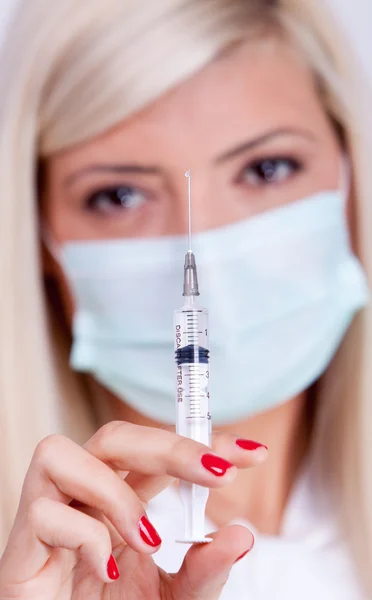 Женщина-врач или медсестра в медицинской маске держит шприц с инъекцией — стоковое фото
