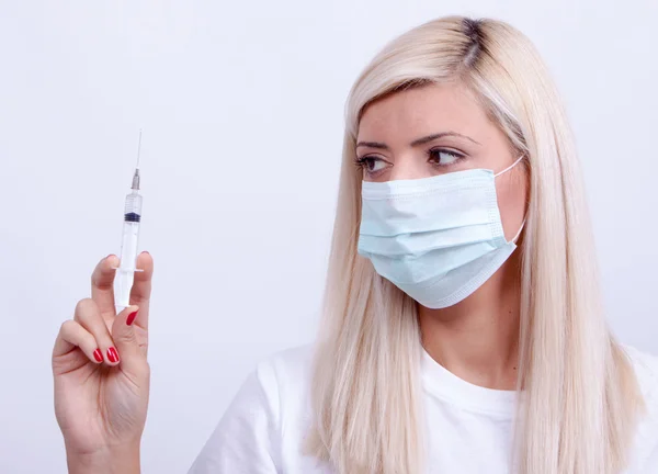 Жінка-лікар або медсестра в медичній масці тримає шприц з ін'єкціями — стокове фото