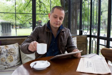 A happy man reading an ebook in a coffee shop