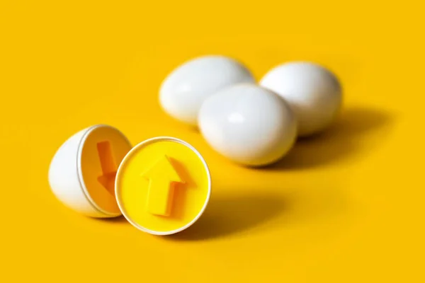 Sarı arka planda ok şeklinde plastik yumurtalar. Renkleri ve şekilleri tanımak ve eşleştirmek için eğitici bir oyuncak. Bulmaca montessori oyun konsepti. Yakın plan, metin için boşluk kopyala