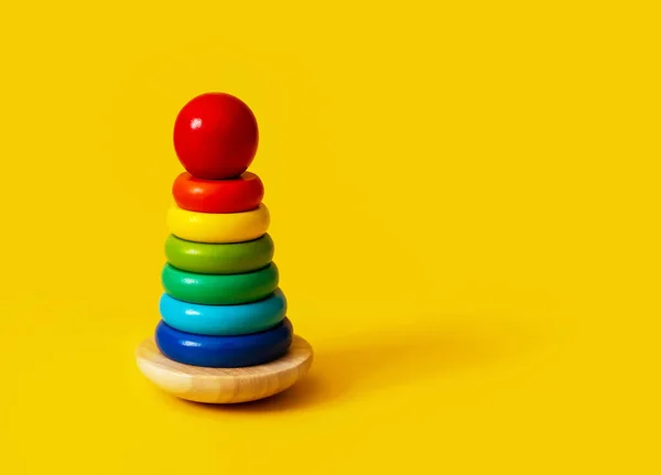 Renkli ahşap bir piramit. Renkleri ve şekilleri tanıyın ve eşleştirin. Bebek konsepti için eğitici montessori oyunu. Yakın plan, metin için boşluk kopyala