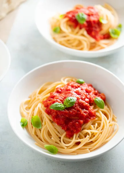 Domates soslu spagetti ve bir tabak fesleğen. — Stok fotoğraf