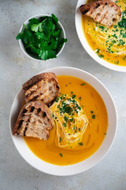 Kabak çorbası kızarmış ekmek, maydanoz ve zeytinyağı ile servis edilir..