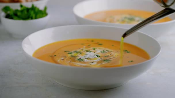 Sopa de abóbora servida em uma tigela com croutons, salsa e azeite. — Vídeo de Stock