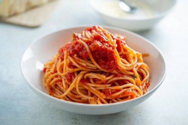 Domates soslu spagetti ve bir tabak fesleğen.