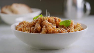 Parmesan peyniri kasedeki makarna tabağına rendeleniyor.