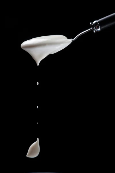 Spoon with yogurt on a black background — Stock Photo, Image