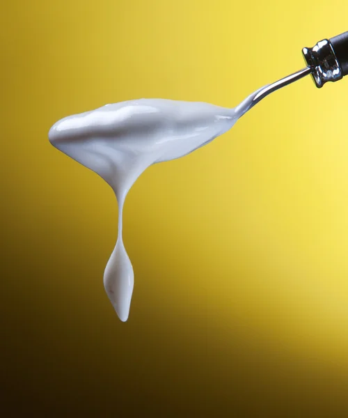Spoon with yogurt on a yellow background — Stock Photo, Image