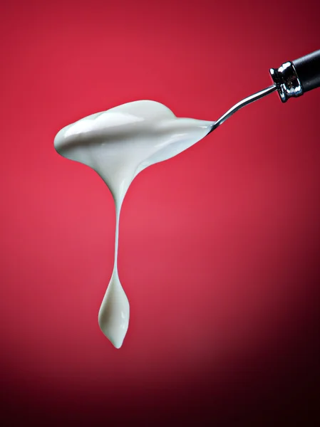 Spoon with yogurt on red — Stock Photo, Image