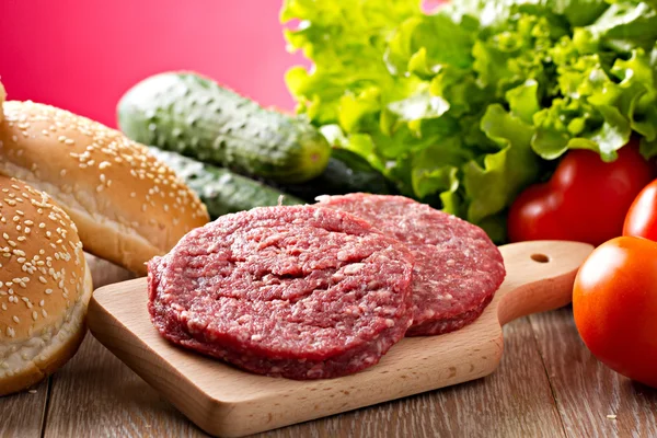 Ingredientes para hambúrgueres em tábua de corte — Fotografia de Stock