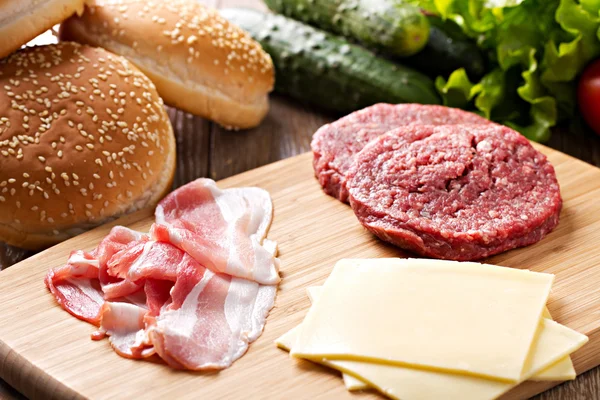 Ingredientes para hambúrgueres em tábua de corte — Fotografia de Stock