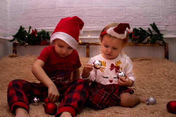 Yeni yıl kıyafetleri içinde Noel süsüsüyle yatakta oturup Noel ağaçlarıyla oynuyorlar.