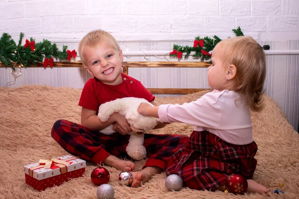 Fratello e sorella di aspetto slavo litigano per il giocattolo. Ragazzo ride la ragazza è insoddisfatta. Mio fratello porta via il giocattolo a sua sorella. Regali di Capodanno per bambini — Foto Stock