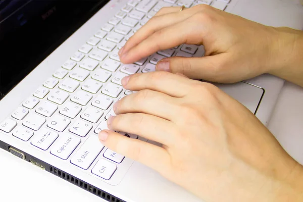 Uma pessoa usando um computador portátil sentado em cima de um teclado — Fotografia de Stock