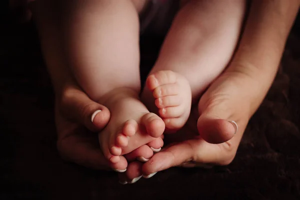 Childrens feet in the hands of the mother. — Stock Photo, Image