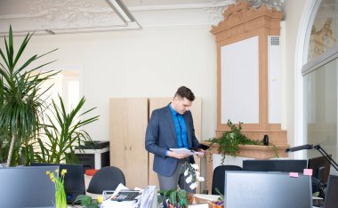 Modern ofiste hesap makinesi ve belge tutan genç bir işadamı.