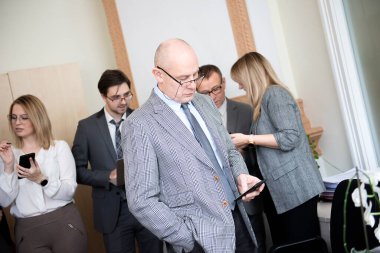 İşadamı mimar ofisin arkasındaki meslektaşlarıyla cep telefonu kullanıyor