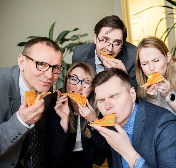 business, food, lunch and people concept - happy business team eating pizza in office