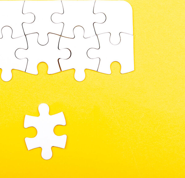 white jigsaw puzzle isolated on a yellow background 