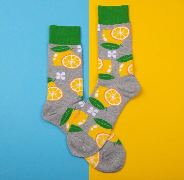 Mavi ve sarı arka plan, limon ve yeşil yapraklar üzerinde izole edilmiş bir çift çorap ile renkli düz yatıyordu.