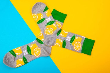 Mavi ve sarı arka plan, limon ve yeşil yapraklar üzerinde izole edilmiş bir çift çorap ile renkli düz yatıyordu.