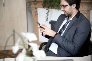 Gülümseyen yakışıklı serbest yazar ev ofisinden uzaktan çalışıyor. Telefonla konuşuyor..