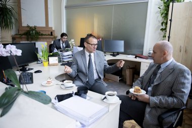 İş arkadaşları çalışma masasında kahve molası veriyorlar.