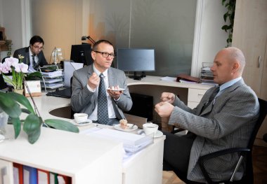 İş arkadaşları çalışma masasında kahve molası veriyorlar.