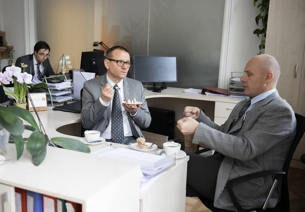 İş arkadaşları çalışma masasında kahve molası veriyorlar.