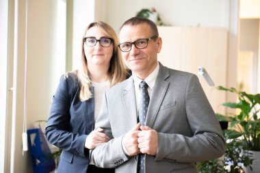 İyi görünümlü orta yaşlı bir iş adamı ve kameraya gülümseyen bir çift.