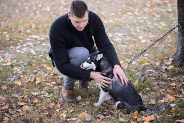 Sonbahar parkında köpeği olan genç bir hayvan sahibi.