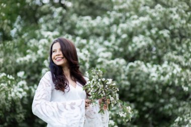 Parktaki güzel bir genç kadının portresi Yazın veya ilkbaharda açan dallarda.