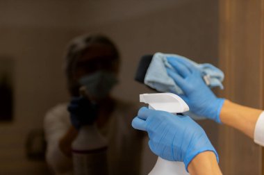 Koruyucu eldivenler ve takım elbiseli bir kadın sauna alanlarında temizlik ve dezenfeksiyon yapıyor..