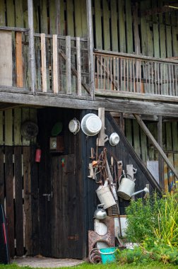 Letonya 'da eski metal aletler, tavalar ve sulama kutularıyla dekore edilmiş kırsal bir ahır duvarı nostaljik bir kırsal atmosfer yaratır..