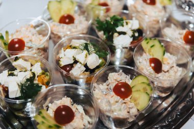 Letonya 'da kutlama sırasında şeffaf bardaklarda servis edilen düğün salatası porsiyonları.