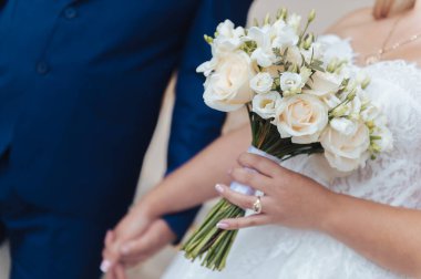 Latvi 'deki tören sırasında damadın yanında dururken beyaz düğün buketi tutan orta yaşlı gelinin yakın görüntüsü