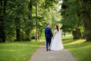 Orta yaşlı yeni evliler, uzun ağaçlarla çevrili güneşli bir park yolu boyunca yan yana yürürler. Uyum, denge ve hayat yönlerini tören üstüne paylaşırlar..