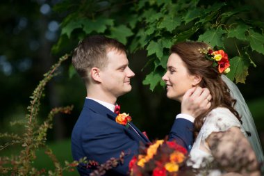 Damat gelinin eline uzanırken, kırmızı duman orman yolunu arkalarından dolduruyor.