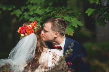 Damat gelinin eline uzanırken, kırmızı duman orman yolunu arkalarından dolduruyor.