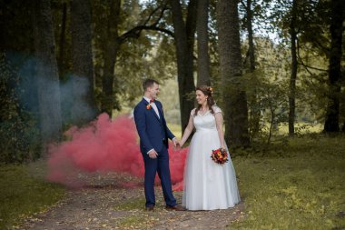 Gelin ve damat sessiz bir orman yolunda karşı karşıya duruyorlar. Derin kırmızı duman arkalarında sürükleniyor ve dramatik ve romantik bir açık hava düğün sahnesi yaratıyor..