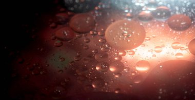 Sıvı, yumuşak ışık geçişleri ve zengin derinlikte parlayan sıcak turuncu yağ damlacıkları ile yatay soyut arka plan. Premium görsel projeler için uygun sanatsal makro doku.