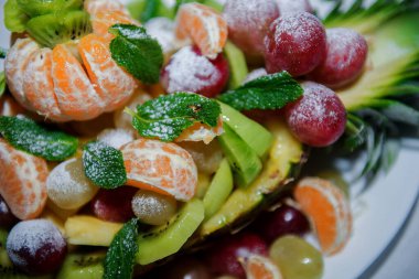 Ananas kivi, nane yaprağı ve pudra şekeri içeren zarif bir düğün meyvesi dekorasyonunun canlı bir tatlı kompozisyonu oluşturması..