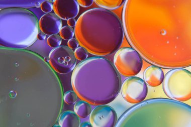 Petrol damlalarının soyut bir fotoğrafı suyun üzerinde yüzüyor.