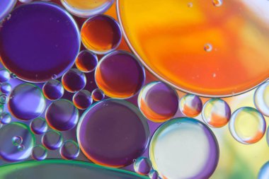 Petrol damlalarının soyut bir fotoğrafı suyun üzerinde yüzüyor.