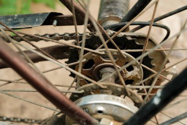 Paslı dişli ve zincirli bisiklet tekerleği merkezinin yakın çekimi, tellerin ve mekanik bileşenlerin karmaşık detaylarını gösteriyor.