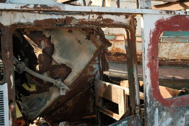 Terk edilmiş ve paslanmış bir tekne içi. Çürüme ve ihmal üzerine odaklanmış, soyulmuş boyalar ve paslanmış metal yüzeyler.
