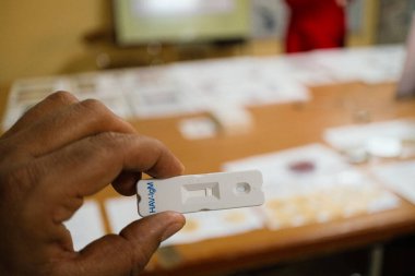 Tıbbi test kiti tutan kişinin geçmişinde çeşitli tıbbi malzemelerle dolu bir masa var.