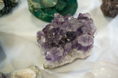 Beyaz bir yüzeyde bulunan mor ametist kristallerinden oluşan bir küme doğal güzelliklerini ve eşsiz oluşumlarını gözler önüne seriyor.